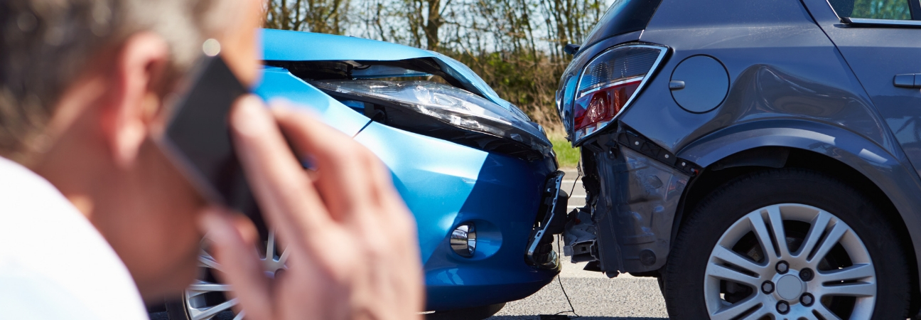 Man on the phone in front of a fender bender
