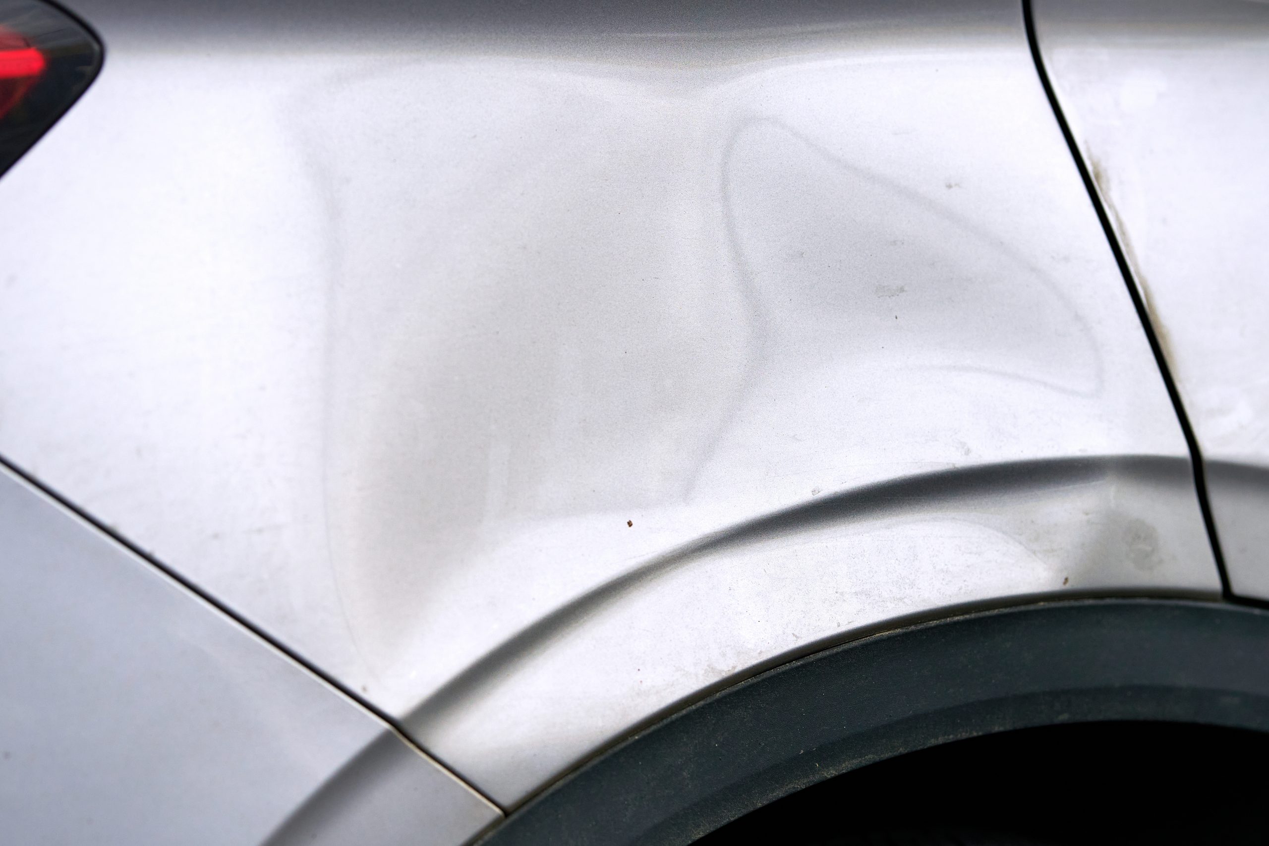 Dented,,Scratched,Car,Body,Near,Rear,Wheel,Arch,Showing,Paint